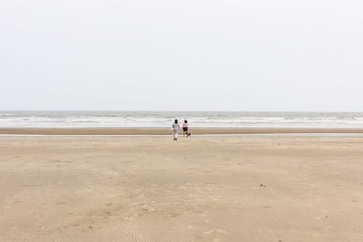 Men on beach against clear sky