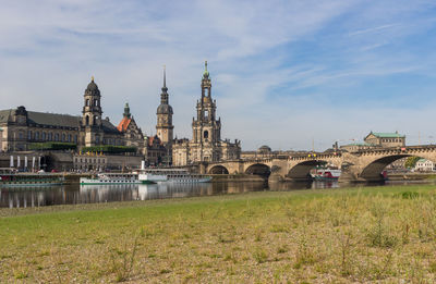 Arch bridge over river by buildings against sky in city