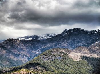 Scenic view of mountains against cloudy sky during winter