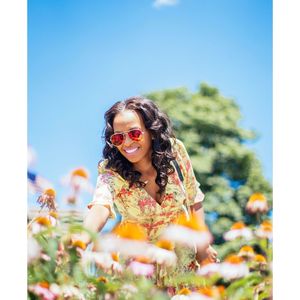 Portrait of young woman wearing sunglasses while sitting on field