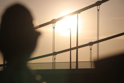 Silhouette person by bridge against sky during sunset