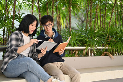 Young woman using laptop while sitting against plants