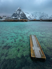 Scenic view of sea by snowcapped mountain against sky