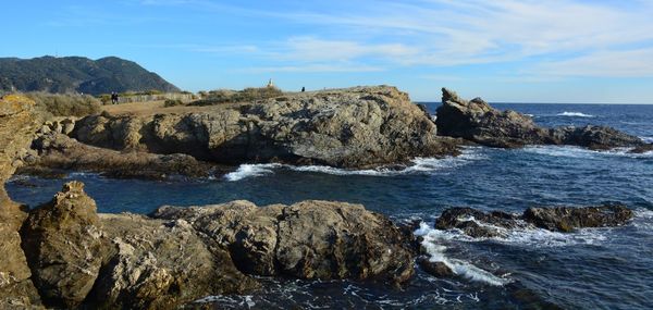 Rocks on shore by sea against sky