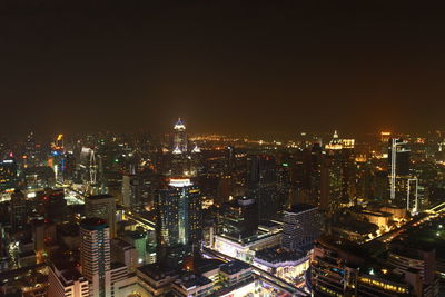 Illuminated modern buildings in city against sky at night