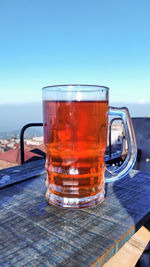 Close-up of beer glass on table against sky
