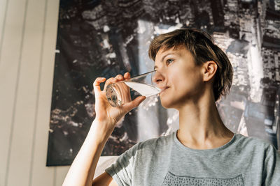A young woman drinks water sitting at home