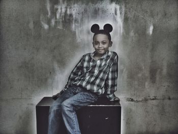 Portrait of smiling boy sitting against wall