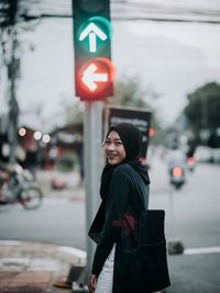 Portrait of smiling woman standing on road in city