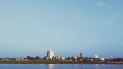 River in front of cityscape against clear sky