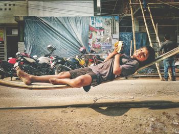 Full length of teenage boy eating banana while lying on wood