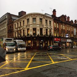 Cars on road by buildings against sky in city