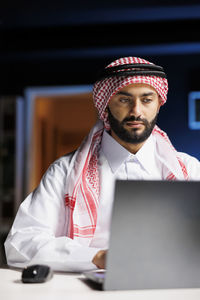 Portrait of young man using laptop while sitting on table