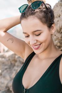 Close-up of smiling young woman standing against rock formation