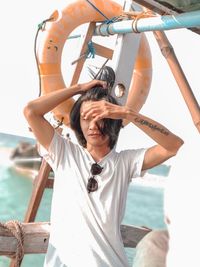 Young man with arms raised against sea