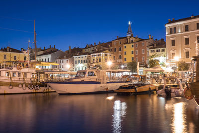 Boats moored in canal by buildings against clear sky at night