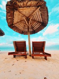 Chair on beach against sky