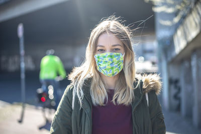 Sick young woman wearing mask standing in city