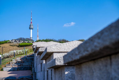 Lighthouse by sea against clear blue sky