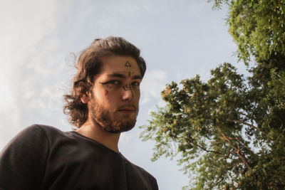 Portrait of young man looking away against sky