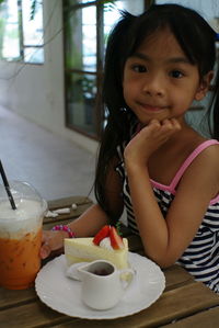 Portrait of cute girl with drink on table