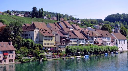 Houses by lake and buildings against clear sky