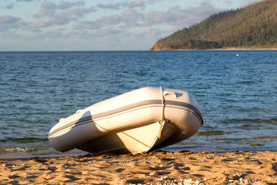 Boat moored on sea shore against sky