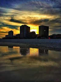 Cityscape against cloudy sky at sunset