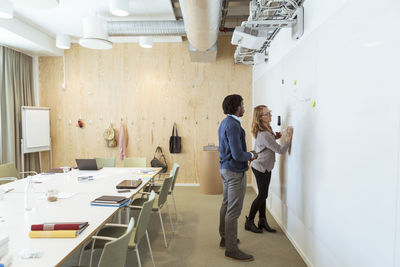 Full length of male and female colleagues discussing over business plan in board room