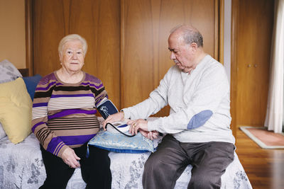 Senior man checking blood pressure of his wife at home