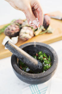 Hands putting spices into mortar