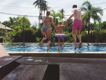 Children standing in swimming pool against sky