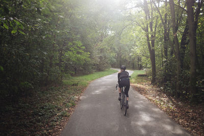 Rear view of man riding bicycle on road