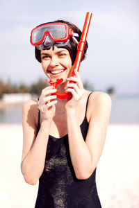 Portrait of young woman with arms raised standing at beach