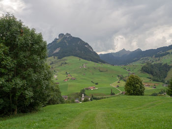 Scenic view of green landscape and mountains against sky