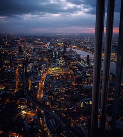 High angle view of illuminated buildings and thames river seen through window at dusk