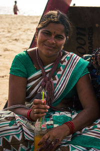 Portrait of young woman sitting at beach and smiling showing nice emotion