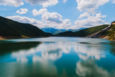 Scenic view of river amidst mountains against cloudy sky