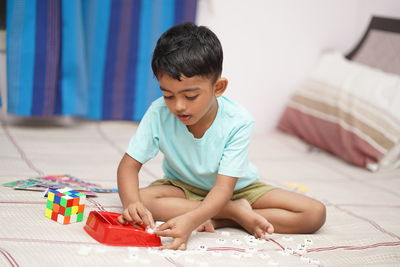 Side view of boy reading book at home