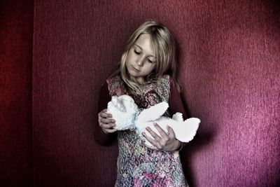 Girl holding toy against wall