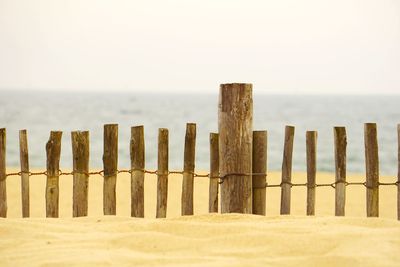 Wooden fence on beach against sky