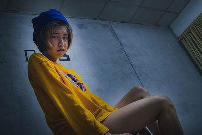 Portrait of woman sitting against wall at home