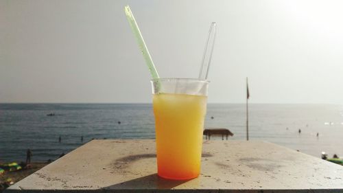 Close-up of drink on beach against sky