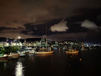 Boats moored at illuminated harbor against sky at night