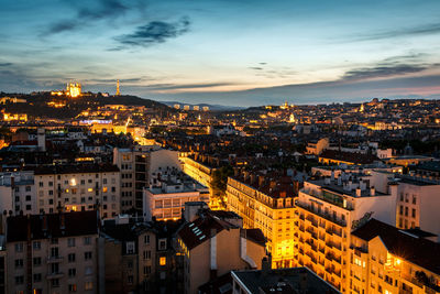 High angle view of illuminated city buildings against sky at sunset