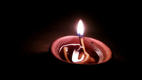 Close-up of illuminated candle over black background