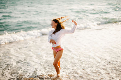 Full length of young woman standing at beach