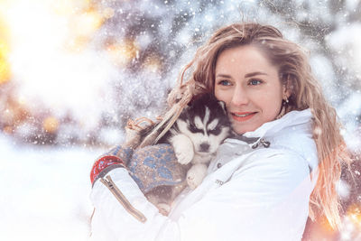 Portrait of smiling young woman standing against snow