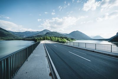 Empty road leading towards mountains against sky