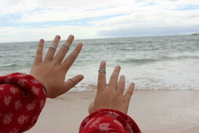 Low section of child on beach against sky